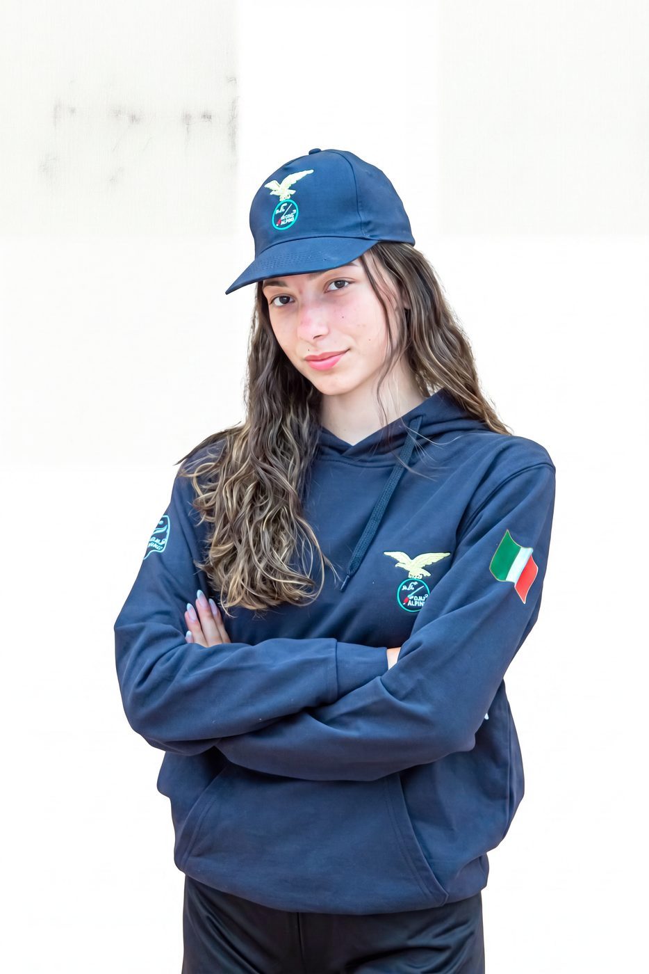 Ragazza a braccia conserte con felpa blu con cappuccio e cappellino blu ricamati