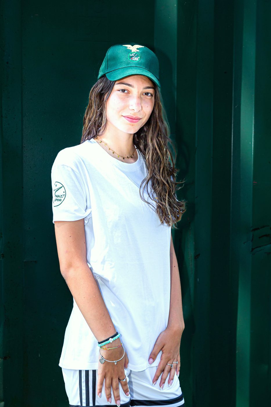 Ragazza con maglietta bianca Alpini e cappellino verde