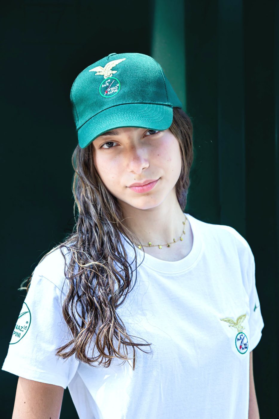 Cappellino verde Alpini con aquila ricamata indossato da una ragazza