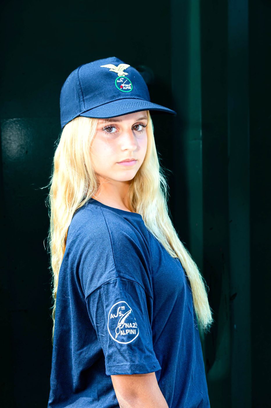 Ragazza di profilo con cappellino blu Alpini e maglietta blu