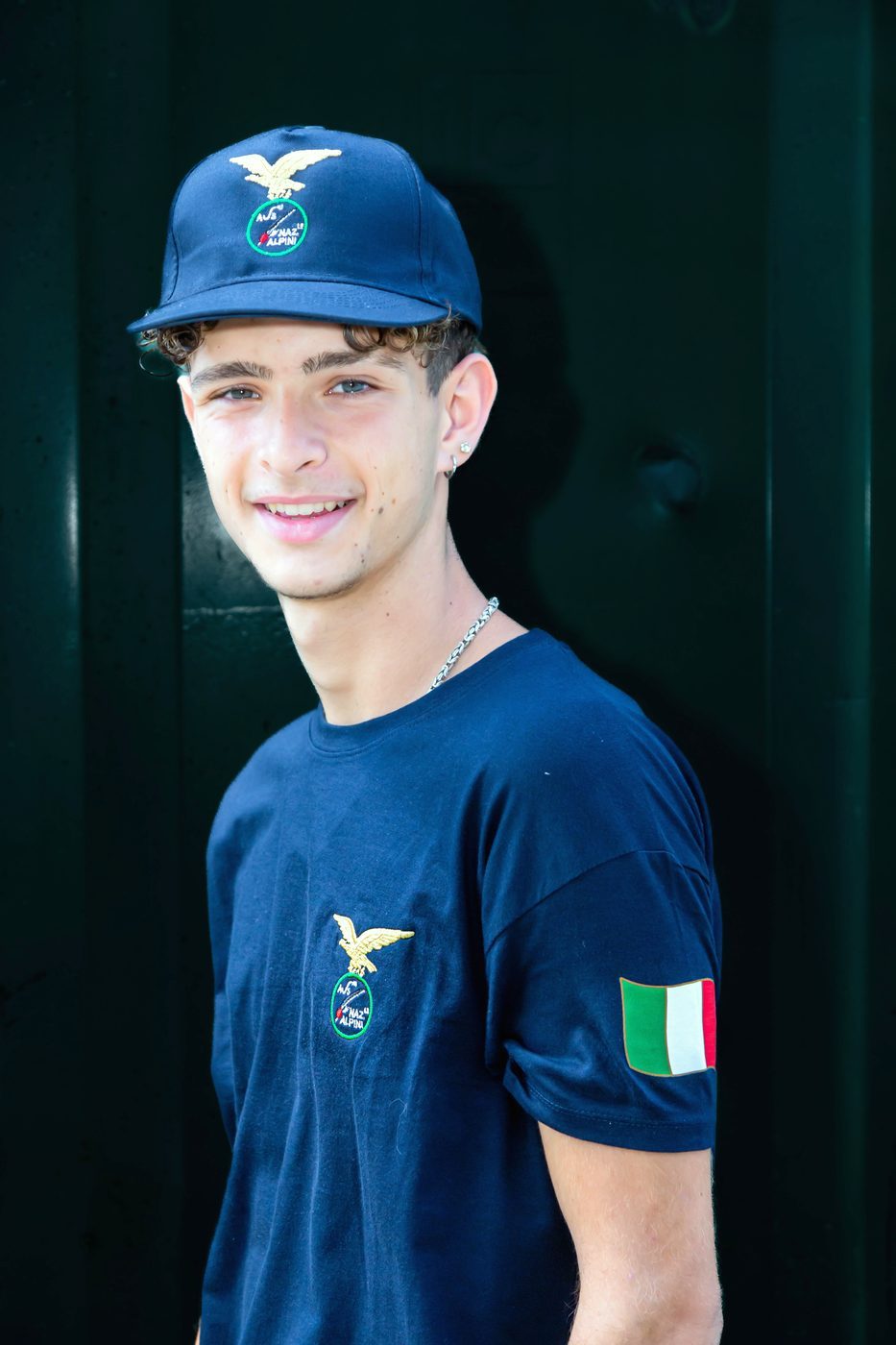 Ragazzo con cappellino blu e maglietta blu con bandiera italiana sulla manica