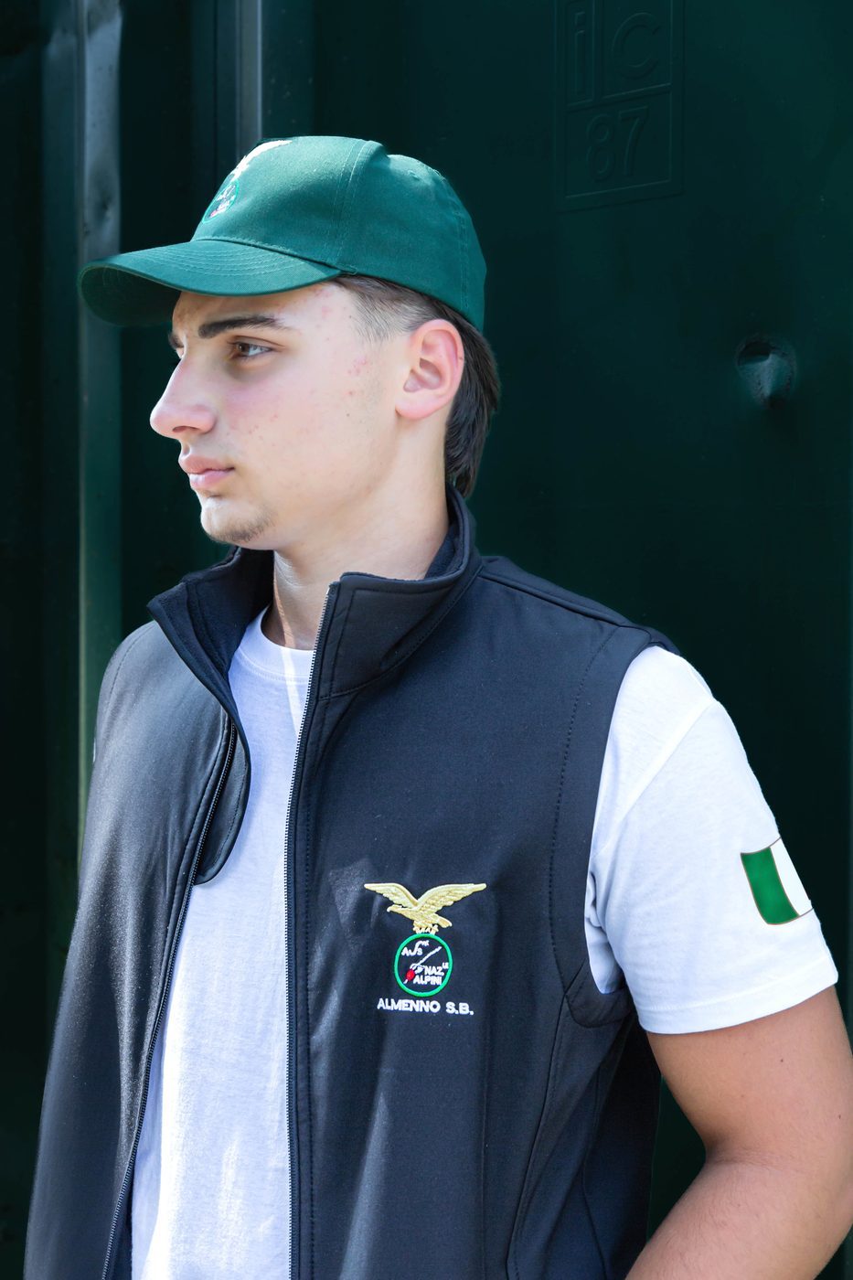 Cappellino verde Alpini visto di profilo, con gilet nero ricamato Almenno S.B.