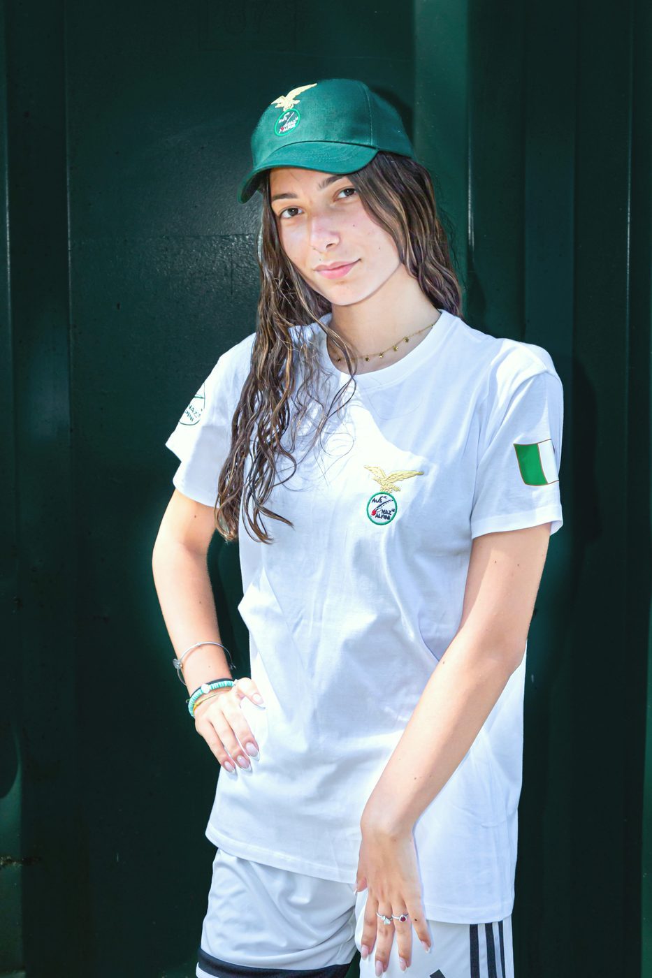 Ragazza con maglietta bianca Alpini con aquila ricamata e cappellino verde