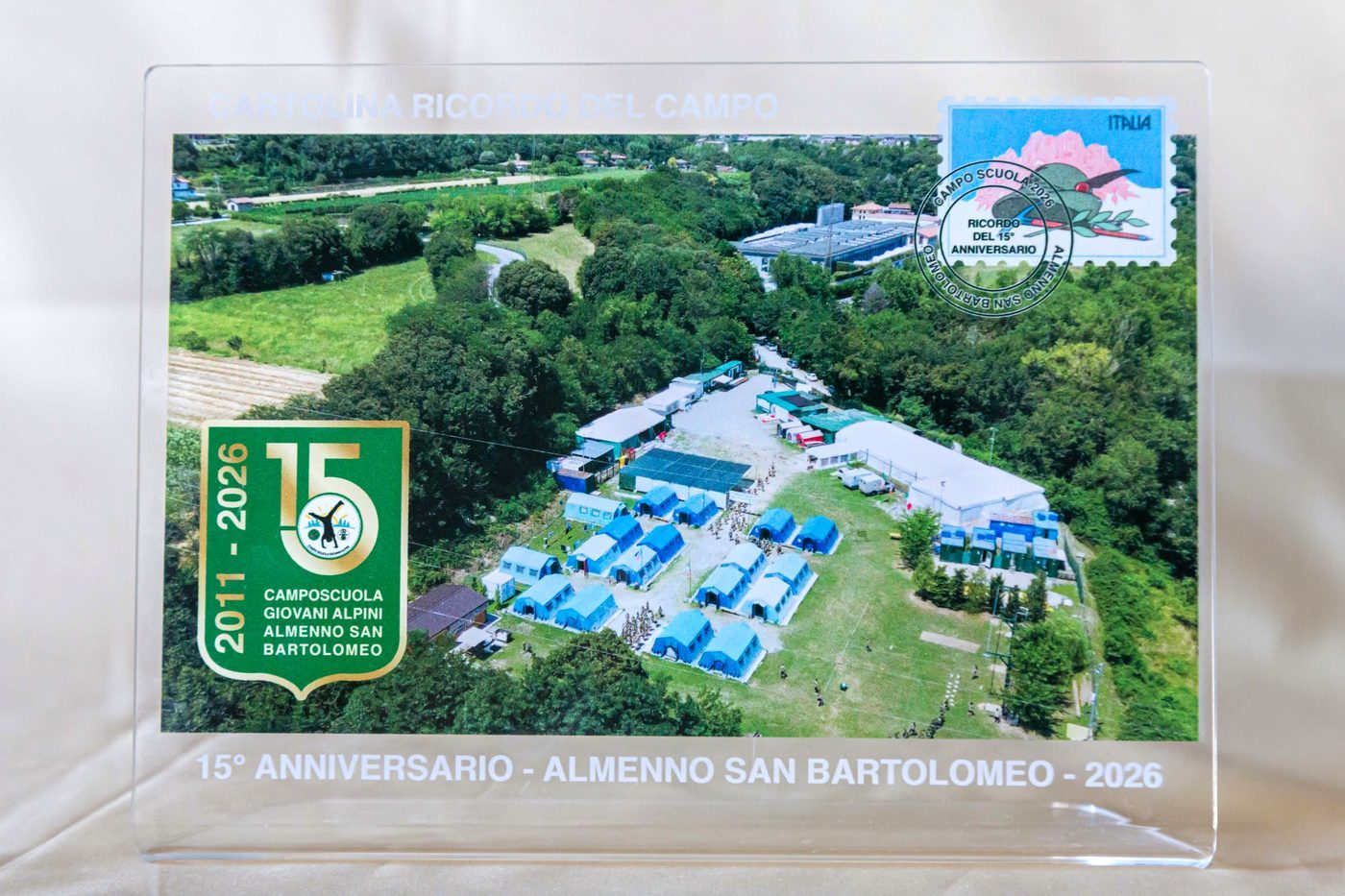 Cartolina ricordo in plexiglass con foto aerea del campo e francobollo del 15° anniversario