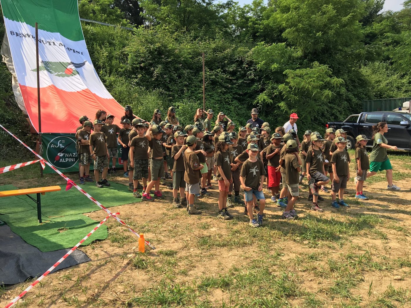 In fila sotto la bandiera Benvenuti Alpini